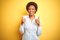 African american business woman over isolated yellow background success sign doing positive gesture with hand, thumbs up smiling Royalty Free Stock Photo