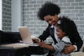 African american business woman taking care of her little daughter while working at home Royalty Free Stock Photo