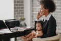 African american business woman taking care of her baby boy while working at home