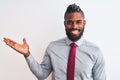 African american businessman with braids wearing tie standing over isolated white background smiling cheerful presenting and Royalty Free Stock Photo