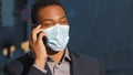 African American businessman ethnic man male guy in medical face mask talking mobile phone answer call talk with Royalty Free Stock Photo