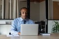 African American businessman in headphones speaking, looking at laptop screen