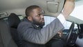 African-American businessman looking in car mirror to smarten beard and tie