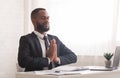 African american businessman praying with closed eyes in office