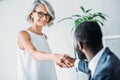 african american businessman and smiling caucasian businesswoman shaking hands Royalty Free Stock Photo
