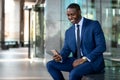 African american businessman smiling cheerful, using cell phone at office building, internet, broadband, 5G, copy space Royalty Free Stock Photo