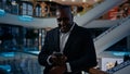 African American businessman standing in shopping mall company office man looking at mobile phone talk has video call Royalty Free Stock Photo