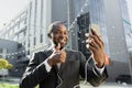 An African American businessman in a suit and headphones is standing outside an office center and talking on a video Royalty Free Stock Photo