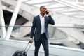 African American Businessman Talking On Cellphone While Walking With Luggage In Airport Royalty Free Stock Photo