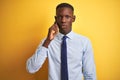 African american businessman talking on smartphone standing over isolated yellow background with a confident expression on smart Royalty Free Stock Photo