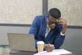 African American businessman working with documents with charts and diagrams top view, sitting at desk, using laptop, looking at Royalty Free Stock Photo