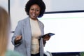 African american businesswoman holding digital tablet and giving presentation to business colleagues Royalty Free Stock Photo