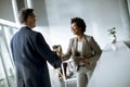 Businesswoman holding digital tablet and looking at handsome colleague while shaking hands in office Royalty Free Stock Photo