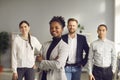 African-American businesswoman standing arms folded and smiling with team of workers behind