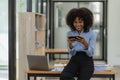 African-American businesswoman working on laptop at office using smartphone and financial graphs, Royalty Free Stock Photo