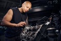 African-American car maintenance station worker repairing some details in engine