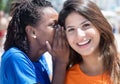 African american and caucasian girlfriend whispering in the city Royalty Free Stock Photo