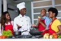 African american chef teaching women and men at kitchen