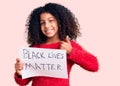 African american child with curly hair holding black lives matter banner smiling happy and positive, thumb up doing excellent and