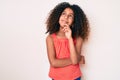 African american child with curly hair wearing casual clothes thinking concentrated about doubt with finger on chin and looking up