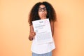 African american child with curly hair wearing glasses showing a passed exam covering mouth with hand, shocked and afraid for Royalty Free Stock Photo