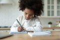 African american child girl handwriting school tasks alone at home.