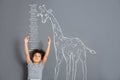 African-American child measuring height near chalk giraffe drawing on grey Royalty Free Stock Photo