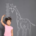 African-American child measuring height near chalk giraffe drawing Royalty Free Stock Photo