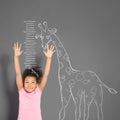 African-American child measuring height near chalk giraffe drawing on wall Royalty Free Stock Photo