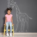 African-American child near grey wall with chalk giraffe drawing Royalty Free Stock Photo