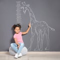 African-American child near grey wall with chalk giraffe drawing Royalty Free Stock Photo