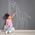 African-American child near grey wall with chalk giraffe drawing Royalty Free Stock Photo