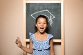 African-American child standing at blackboard with chalk drawn academic cap. Royalty Free Stock Photo