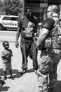 African American Child Stares Up at Armed White Militia Member
