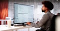 African American Coder Using Computer At Desk