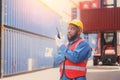 African American container operators wearing yellow helmets and safety vests control via walkie-talkie workers in container yards