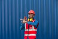 African American Container Warehouse Worker. Foreman control loading Containers box from Cargo freight ship for import export.