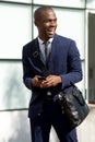 African american corporate businessman walking in city with mobile phone Royalty Free Stock Photo