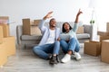 African american couple discussing design of new flat, sitting on floor and using digital tablet, planning renovation Royalty Free Stock Photo