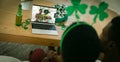 African american couple having st patrick\'s day video call with male friends on laptop at home