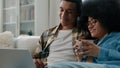 African American couple at home couch looking at laptop talking watching film movie discuss choosing goods online store Royalty Free Stock Photo