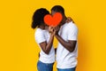 African american couple kissing and hiding behind red heart Royalty Free Stock Photo