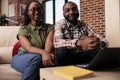 African american couple living together binging online series on laptop looking at screen