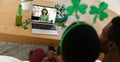 African american couple making st patrick\'s day video call with female friend on laptop at home