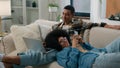 African American couple man with laptop computer sitting on couch home woman chatting smartphone browsing mobile phone Royalty Free Stock Photo