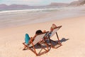 African american couple relaxing on deckchairs at sandy beach during sunny day, copy space