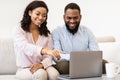 African american couple sitting on couch, using laptop Royalty Free Stock Photo