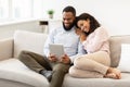 African american couple sitting on couch, using tablet Royalty Free Stock Photo