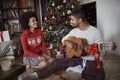 African American couple sitting on floor together and listening guitar songs at home on Christmas holiday Royalty Free Stock Photo