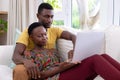 African american couple sitting on sofa using laptop computer and smiling Royalty Free Stock Photo